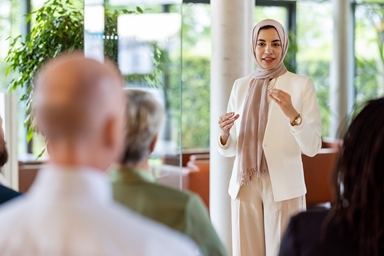 woman with white suit and headscarf engaging an audience